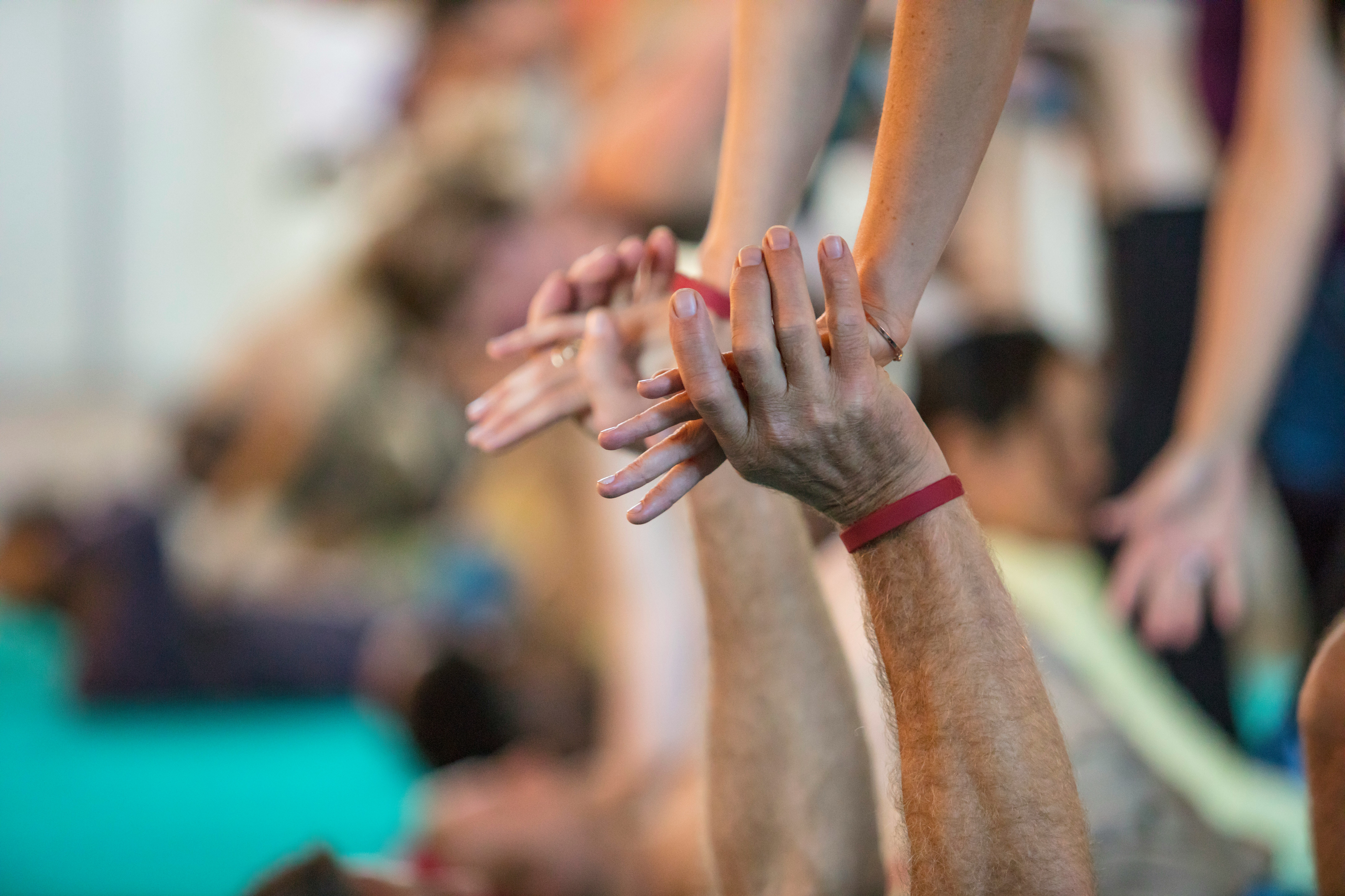 Verschr&auml;nkte H&auml;nde beim Partner-Yoga, verschwommener Hintergrund.